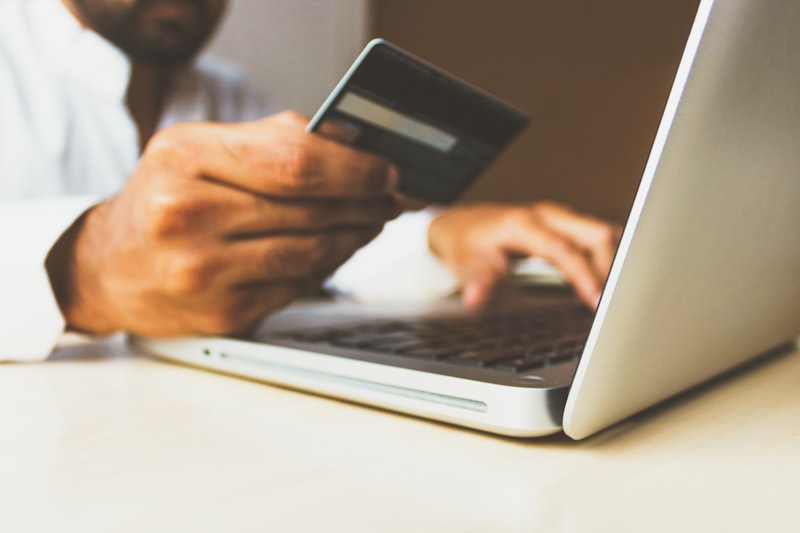 Person holding credit card while checking out on a laptop